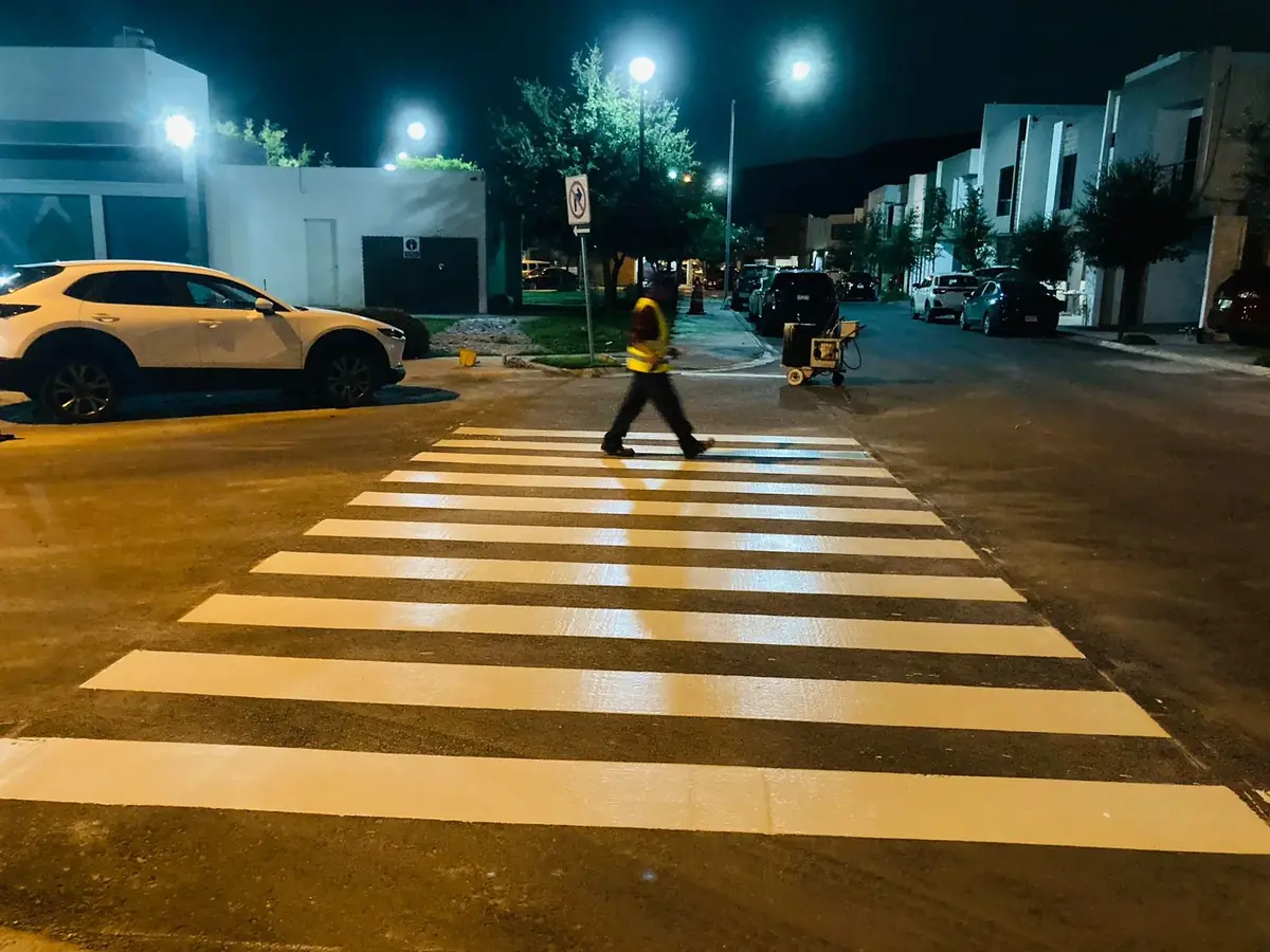 Cebra peatonal pintada de noche en zona residencial — señalamiento horizontal